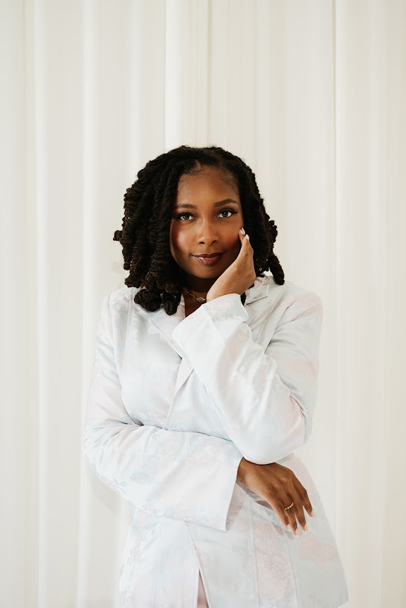 Kierra Dotson in a white blazer, hand resting near her face